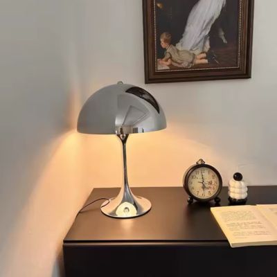 lampe champignon design chromée allumée sur commode réveil matin et livre ouvert