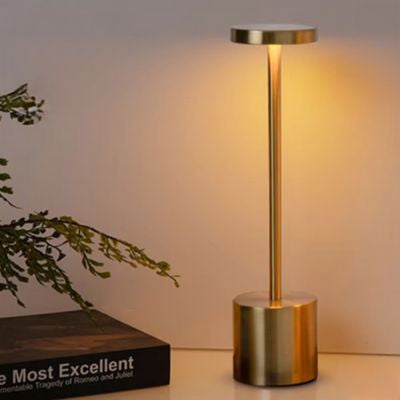 lampe de chevet LED dorée allumée USB sur bureau un livre branches et feuilles vertes
