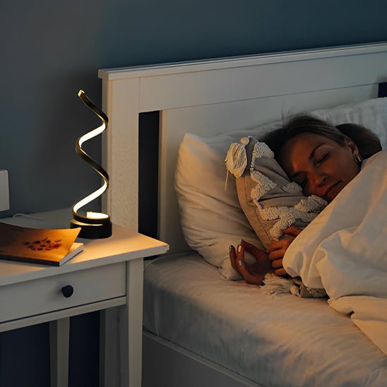 lampe de chevet spirale noire sur une table de nuit une femme dort dans des draps blancs