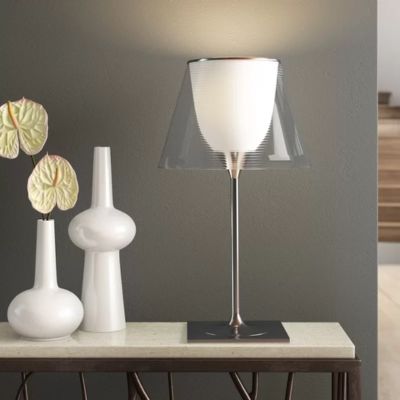 lampe de table Led design italien postmoderne métal chromé et verre transparent sur crédence blanche et fer couleur cuivre 2 bibelots blancs mur du fond gris très pâle