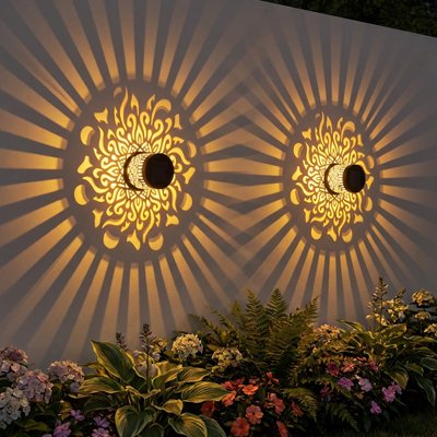 Éclairage extérieur mural décoratives soleil doré projetant motifs lumineux rayonnants sur mur extérieur avec plantes fleuries