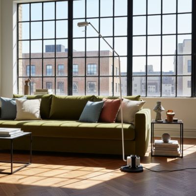 lampadaire design blanc minimaliste articulé dans loft grande fenêtre noir à carreaux grand canapé vert olive