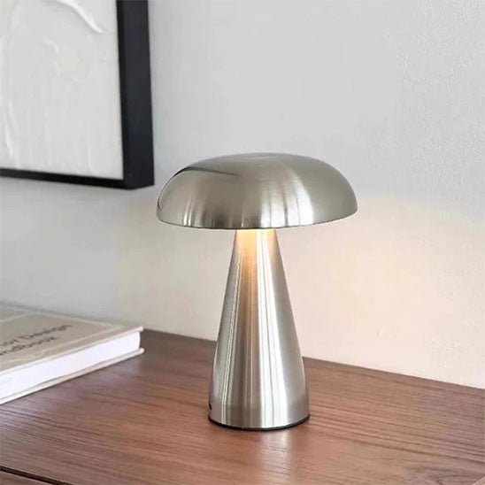 lampe champignon argent métal sur bureau en bois un livre derrière partie d'un cadre noir