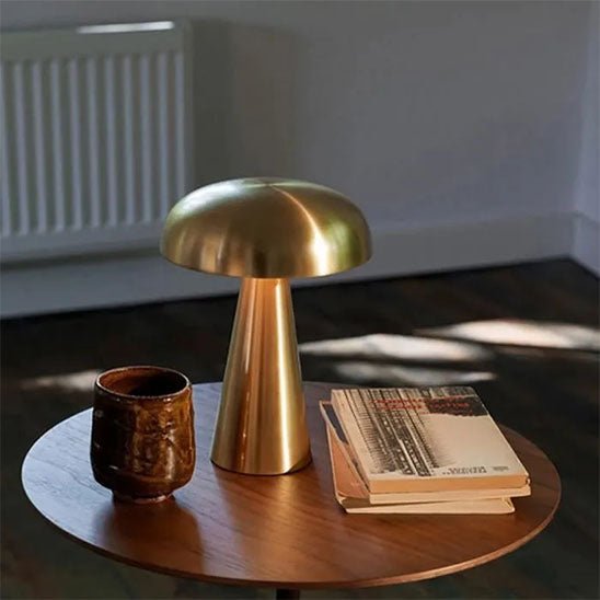 lampe champignon dorée métal sur table en bois des livres et un verre rechargeable 3 ambiances