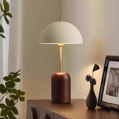 Lampe champignon allumée bois et fer sur commode plante verte cadre noir sculpture