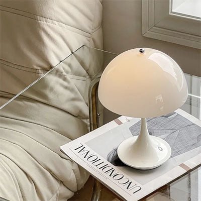 lampe champignon blanche  sur table d'appoint en cristal transparent avec revue blanche un canapé en cuir blanc