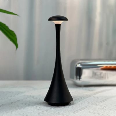 lampe champignon design noire allumée table blanche rideaux blancs feuilles vertes