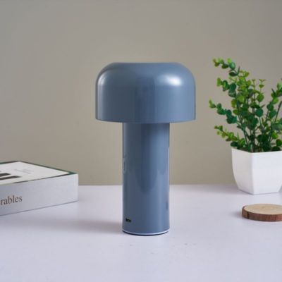 lampe champignon grise sur table blanche un livre et petite plante dans pot blanc