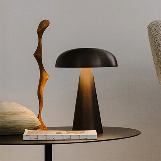 lampe champignon métal noire sur table ronde un livre et une sculpture en bois déco LED rechargeable 3 ambiances