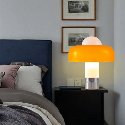 lampe champignon orange allumée sur table de chevet noire dans chambre