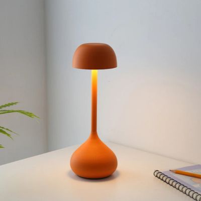 lampe champignon allumée orange mate table blanche cahier notes et crayon