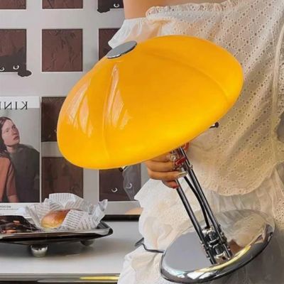 lampe champignon orange vintage allumée abat-jour pied chromé dans main une jeune femme 