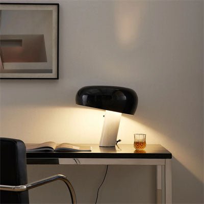 lampe champignon pied marbre blanc abat-jour noir allumée livre ouvert chaise noire et chrome verre sur table noire et chrome