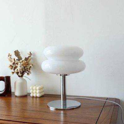 Lampe champignon type macaron abat-jour verre blanc pied chrome USB ajustable sur bureau en bois petite bouteille blanche et fleurs séchées chandelle blanche