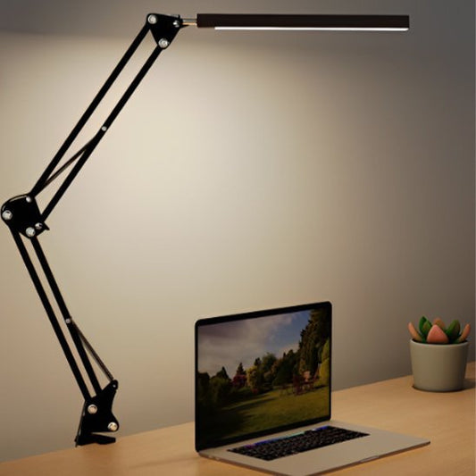 lampe de bureau à clip noire allumée installée sur une table de travail un ordinateur portable est magnifiquement illuminé  