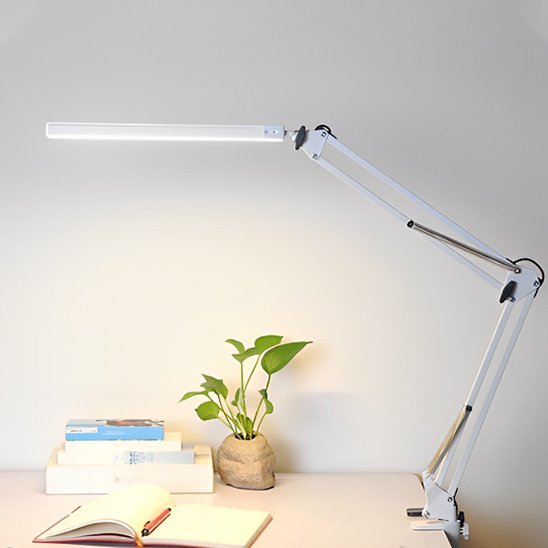 lampe de bureau à clip blanche placée à droite table couleur crème stylo posée sur cahier ouvert derrière une petite plante 3 modes de luminosité 10 intensités pour ajuster à vos besoins