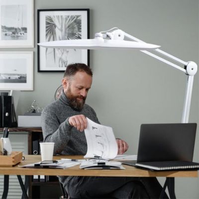  lampe de bureau LED blanche premium articulé homme travaillant bureau bois avec ordinateur portable et documents