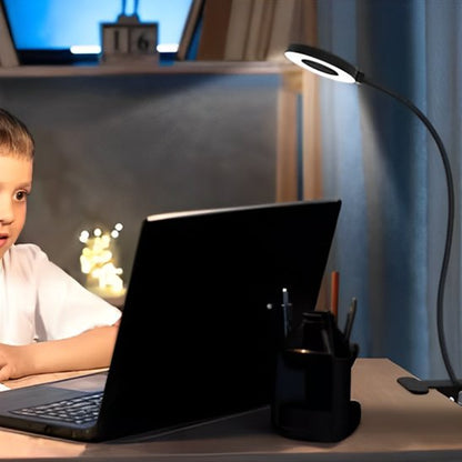 lampe de bureau LED un petit garçon qui fait ses devoirs devant son ordinateur dans la pénombre illuminé par la lampe de bureau flexible