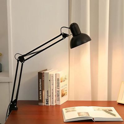 lampe de bureau led à vis fixée à une table en bois elle illumine un livre ouvert