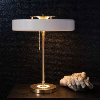 lampe de chevet blanche et dorée  allumée sculpture main fond mur noir texturée style art deco