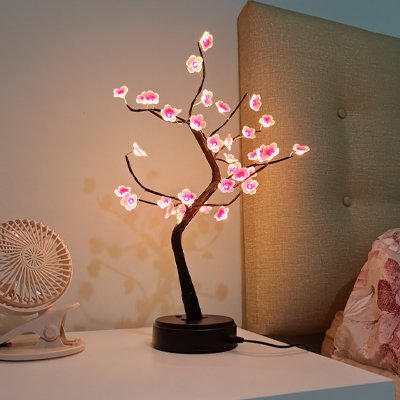Lampe de chevet design forme bonsaï fleurs rose allumées sur table nuit blanche