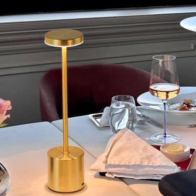 lampe de chevet LED dorée USB type c sur table restaurant avec coupe de-vin et couverts
