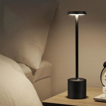 lampe de chevet LED noire mate allumée chambre sur table de nuit lit draps blancs réveil matin