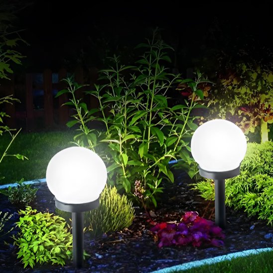 Lampe de jardin boule sur piquet positionnée stratégiquement dans un massif fleuri nocturne