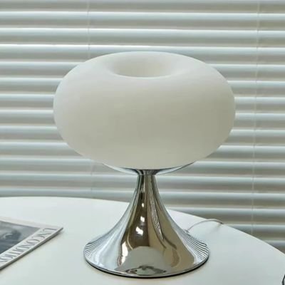 lampe de table blanche style Bauhaus dimmable LED métal chrome et verre sur table ronde blanche une revue derrière persienne blanche