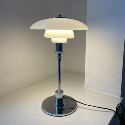 lampe de table blanche danoise filaire allumée sur comptoir blanc  