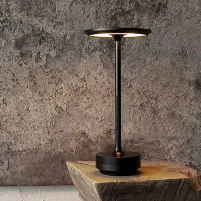 lampe de table design noire minimaliste posée sur bois naturel très épais derrière un mur de ciment gris 