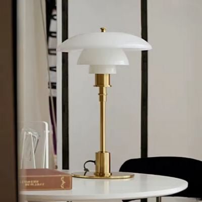 lampe de table pied cuivre sur table ronde blanche un livre 