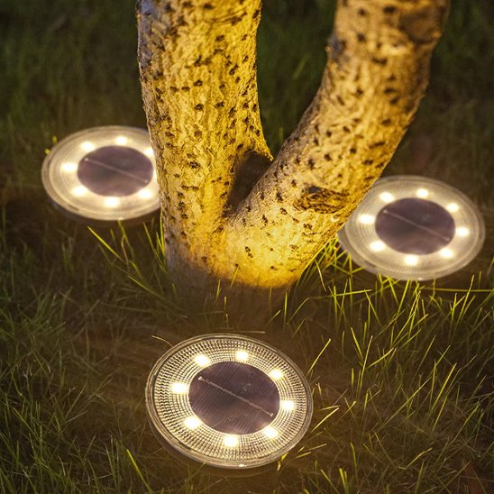 Lampe solaire gardien du sol encastrable au sol installée autour d'un arbre dans une pelouse nocturne