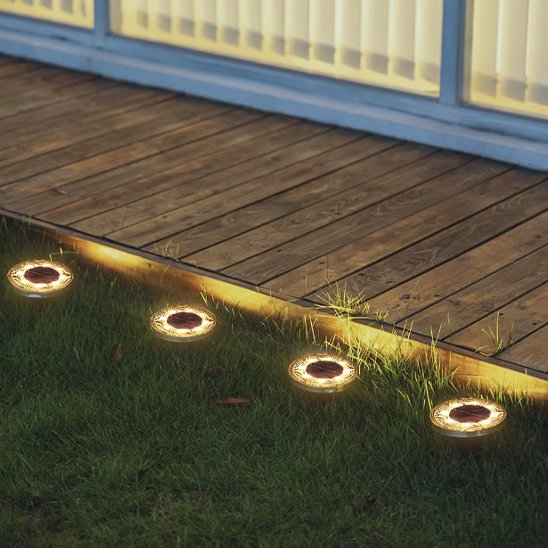 Lampe solaire encastrable au sol positionnés en bordure d'une terrasse en bois, créant un éclairage de délimitation nocturne