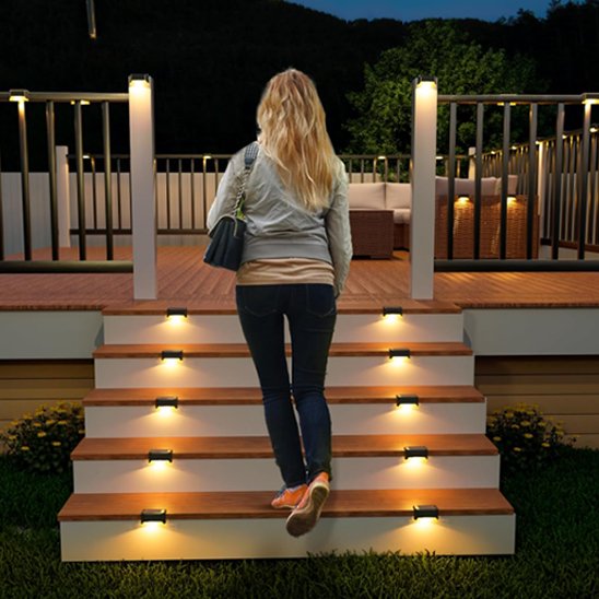Lampe solaire veilleur nocturne noire installée sur escalier extérieur terrasse diffusant lumière chaude vers le bas