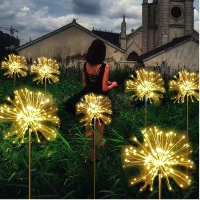 Lampe solaire exterieur étoile filante plusieurs type de feux artifices dans un jardin entourant jeune femme dans la magie