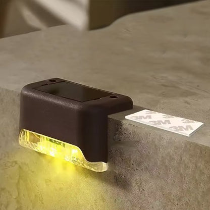 Lampe solaire marron veilleur nocturne fixée sur marche béton diffusant lumière chaude vers le bas