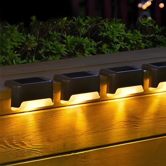 Lampe solaire noire installée sur muret extérieur diffusant lumière chaude vers le bas