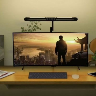 Lampes de bureau pliable moniteur noire éclairant 2 ailes repliées grand écran scène coucher soleil urbain sur bureau jaune avec clavier souris plante et décoration