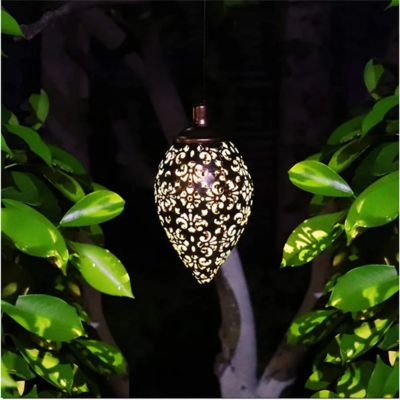 Lanterne solaire en forme d'oeuf métal cuivré ajouré lumière blanche éclairant arbre et feuilles vertes