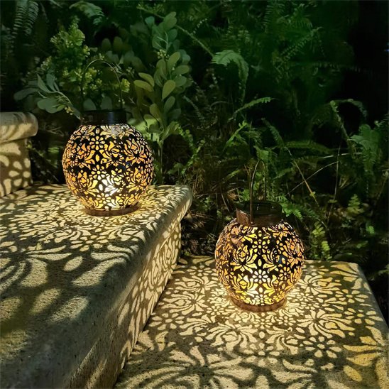 Lanterne solaire boule métal ajouré motifs orientaux il y en a deux allumées la nuit projetant ombres dorées décoratives sur muret pierre