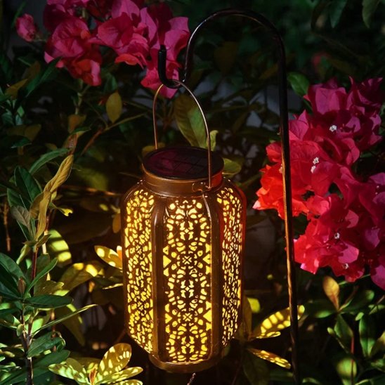 Lumière solaire extérieur LED cuivre ajourée dans massif fleuri roses et bougainvilliers, lumière chaude décorative jardin nocturne