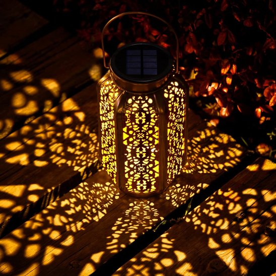 Lumière solaire extérieur LED cuivre ajourée projetant motifs lumineux dorés sur sol et mur, ambiance féérique jardin nocturne