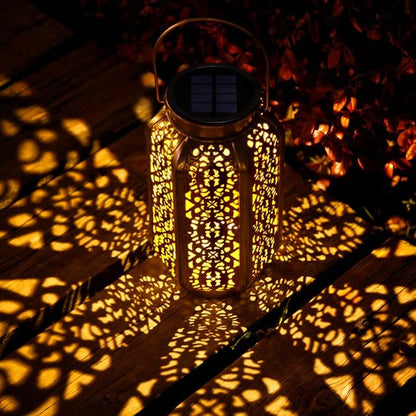 Lumière solaire extérieur LED cuivre ajourée projetant motifs lumineux dorés sur sol et mur, ambiance féérique jardin nocturne