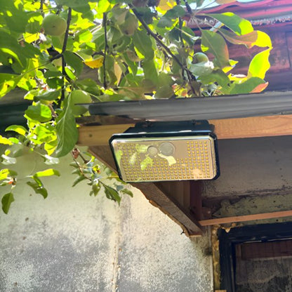 Luminaire exterieur détecteur de mouvement double capteur fixé sous auvent bois maison, feuillage arbre fruitier fond