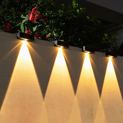 Luminaire extérieur lampes solaires murales noires alignées sur clôture jardin avec fleurs rouges diffusant lumière chaude triangulaire vers le bas